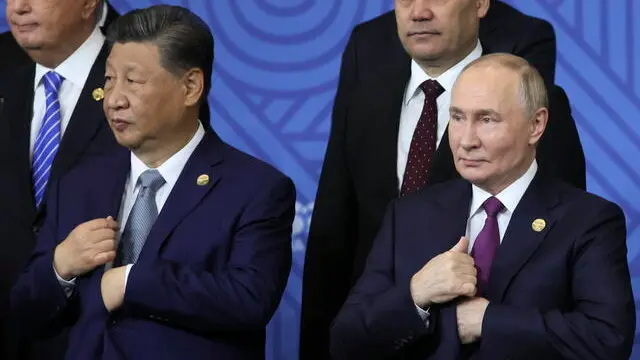 epa11679295 Russian President Vladimir Putin (R) speaks with Chinese President Xi Jinping (2-L) as other participants in the outreach/BRICS Plus format meeting pose for a family photo during the BRICS summit in Kazan, Russia, 24 October 2024. The BRICS summit takes place from 22 to 24 October. EPA/MAXIM SHIPENKOV