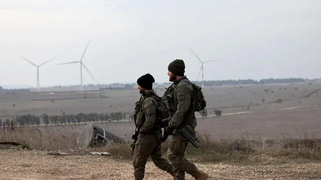 epa11761936 Israeli soldiers walk near the Quneitra crossing, on the Israeli side of the border with Syria, in the Israeli-annexed Golan Heights, 07 December 2024. Following developments in the internal conflict in Syria, Israel's military said it called up additional forces for 'defensive missions' in the Golan Heights area, adjacent to the Israel-Syria border. EPA/ATEF SAFADI