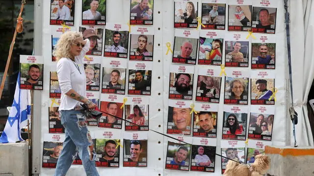 epa11830525 A woman with a dog walks past a display of posters calling for the release of Israeli hostages, who were abducted by militants during the 07 October 2023 Hamas attacks, outside the Kirya military headquarters in Tel Aviv, Israel, 17 January 2025. Israel and Hamas have agreed on a hostage release deal and a Gaza ceasefire to be implemented in the coming days following months of war. Israel's security cabinet is expected to meet on 17 January to approve the agreement. EPA/ABIR SULTAN