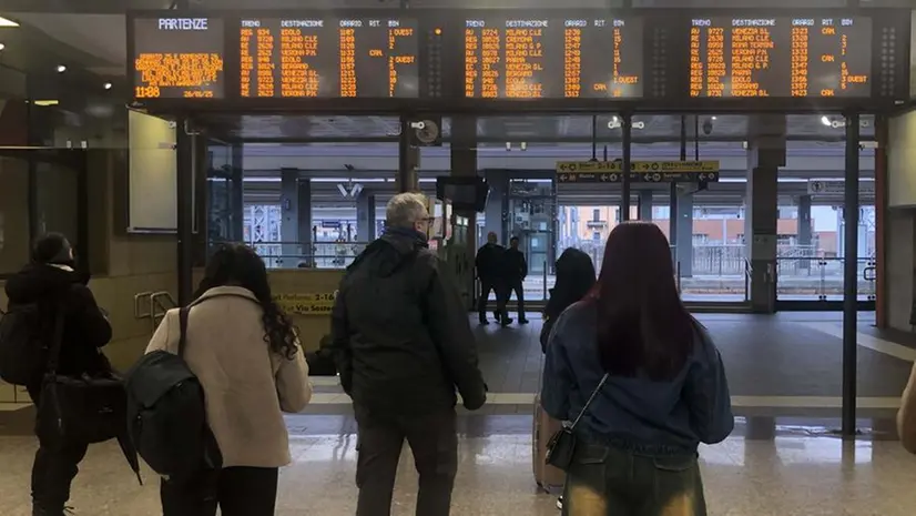 Viaggiatori alla stazione di Brescia, sul tabellone i ritardi - Foto © www.giornaledibrescia.it