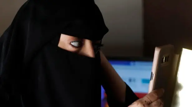 epa09060779 Sound engineer and director Yasmin al-Zudi uses her smartphone camera to adjust her niqab at the Hawa Al-Yemen FM radio station on the eve of International Women's Day, in Sana'a, Yemen, 07 March 2021 (Issued 08 March 2021). Yemeni female journalists dedicate radio programs to address cultural and social issues associated with Yemeni women and promote gender equality and women’s rights, including challenges that prevent them to be empowered in a male-dominated country, especially early marriage and illiteracy among girls. International Women's Day is globally observed on 08 March to highlight the struggles of women around the globe. It was proclaimed by the United Nations General Assembly as the day for women's rights and world peace in 1977. EPA/YAHYA ARHAB