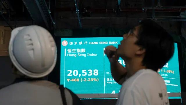 epa11705281 Workers look on as in the background a screen shows the Hang Seng index in Hong Kong, China, 06 November 2024. A few hours after the preliminary US presidential results were announced, Hong Kong's stock market, the Hang Seng Index, fell 2.23 percent. EPA/LEUNG MAN HEI