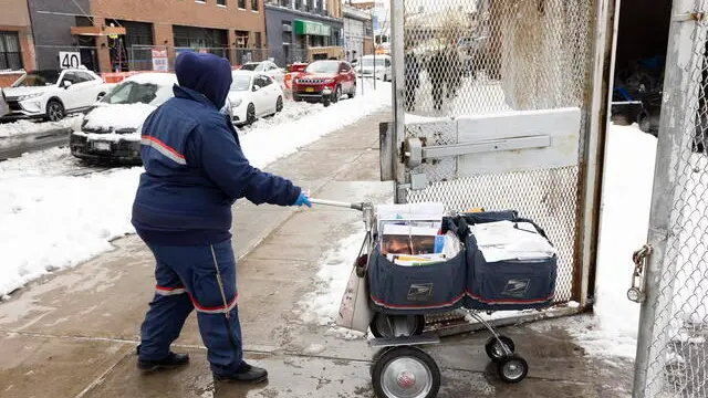 epa08892424 A United States Postal Service worker at a post office in the Brooklyn borough of New York, New York, USA, 18 December 2020. The postal service is facing a massive volume of packages and backlogs as people shop online at record levels and as private package delivery services start to limiting services to some e-commerce retailers, pushing more business to the USPS. EPA/JUSTIN LANE