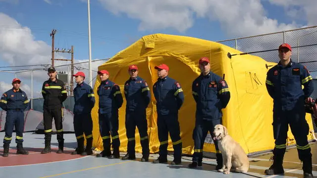 epa11880227 Firefighters and their dog stand in front of a tent during Greek prime minister's visit to Santorini island amid a wave of seismic activity, Greece, 07 February 2025. The municipality of Thera (Santorini) has declared a state of emergency due to a wave of seismic activity, taking effect from 01 February to 01 March. More than 7,700 earthquakes have been detected in the Santorini-Amorgos zone by the Laboratory of Seismology of the National and Kapodistrian University of Athens (NKUA) between 26 January and 04 February, with multiple earthquakes reaching a magnitude of over 4.0 since 04 February. EPA/ORESTIS PANAGIOTOU