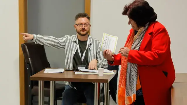 epa11291239 Member of the electoral committee shows the direction to a booth during a vote to remove the mayor of Northern Mitrovica in Northern Mitrovica, Kosovo, 21 April 2024. Four Serb-majority municipalities in northern Kosovo are voting to dismiss the ethnic Albanian mayors of Zvecan, Northern Mitrovica, Zubin Potok, and Leposavic, organized by the government in Pristina. On 17 January 2024, hundreds of residents in the four municipalities signed petitions to dismiss the mayors elected by handfuls of votes as turnout during the elections in April 2023 was up to 5 percent, in the North of Kosovo. For a mayor to be dismissed, 50 percent plus one of the overall number of voters have to vote in favor, but the main Serb party, Srpska Lista, has called residents to boycott the election once again. EPA/GEORGI LICOVSKI