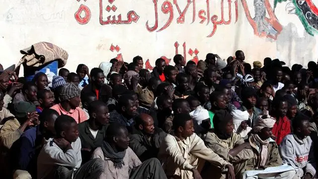 epa03153461 A photo made available on 21 March 2012, shows African migrants in the town of Kufra, southeast Libya, 20 March 2012. According to the UNHCR, about 600 migrants and asylum-seekers are being held in a detention center at Kufra. The UNHCR is working on evacuating them to Benghazi because of fighting in the area between the Tebu and Zwai tribes. EPA/SABRI ELMHEDWI