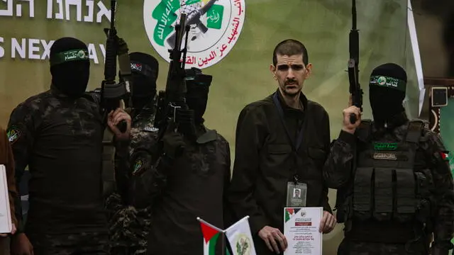 epa11882172 Palestinian fighters from Hamas's Izz ad-Din al-Qassam Brigades escort Israeli hostages Ohad Ben-Ami, Or Levi (pictured) and Eli Sharabi onto the stage before handing them over to a Red Cross team in Deir al-Balah, central Gaza, 08 February 2025. In exchange, Israel will release 183 Palestinian prisoners and detainees. EPA/HAITHAM IMAD