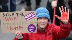 epaselect epa11887553 A demonstrator with red paint on her hands holds up a placard as families of Israeli hostages held by Hamas in Gaza and their supporters protest outside the Israeli Prime Minister's office in Jerusalem, 11 February 2025, calling for the immediate release of the hostages amid an Israel-Hamas hostage release and ceasefire deal. EPA/ABIR SULTAN