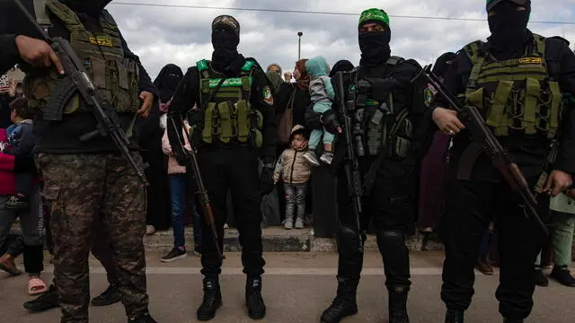 epa11882445 Palestinians with Izz ad-Din al-Qassam fighters after the handing over of three Israeli hostages to the Red Cross as part of a Gaza ceasefire agreement with Israel in Deir al-Balah, central Gaza Strip, 8 February, 2025. In exchange, Israel will release 183 Palestinian prisoners and detainees. EPA/HAITHAM IMAD