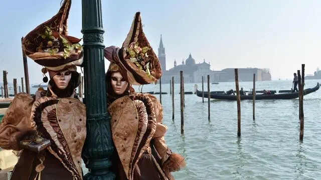 Due persone mascherate in occasione del volo dell'Angelo del Carnevale, in piazza San Marco, Venezia, 8 febbraio 2015. ANSA/ANDREA MEROLA