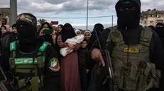 epa11882413 Palestinians with Izz ad-Din al-Qassam fighters after the handing over of three Israeli hostages to the Red Cross as part of a Gaza ceasefire agreement with Israel in Deir al-Balah, central Gaza Strip, 8 February, 2025. In exchange, Israel will release 183 Palestinian prisoners and detainees. EPA/HAITHAM IMAD