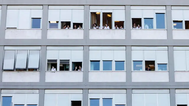 Medical staff and patients watch from windows as Pope Francis leaves the Gemelli Polyclinic Hospital in Rome, Italy, 16 June 2023. The pontiff was discharged from Rome's Gemelli Hospital on 16 June morning, following his recent abdominal surgery to repair a hernia and remove internal scar tissues. ANSA/FABIO FRUSTACI.