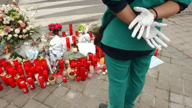 epa00152076 Shaken with grief people put flowers and candles in front of the Santa Eugenia station, a suburb about nine km southeast of Madrid, Friday 12 March 2004, with a security guard showing his white gloved hands, on the day after the worst ever terrorist attack in the history of Spain, which killed nearly 200 people and injured more than 1,400. EPA/FERNANDO ALVARADO