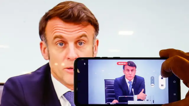 epa11894163 A man takes a photograph of a screen showing French President Emmanuel Macron as he speaks during the International Conference on Syria at the Ministerial Conference Center, in Paris, France, 13 February 2025 EPA/MOHAMMED BADRA