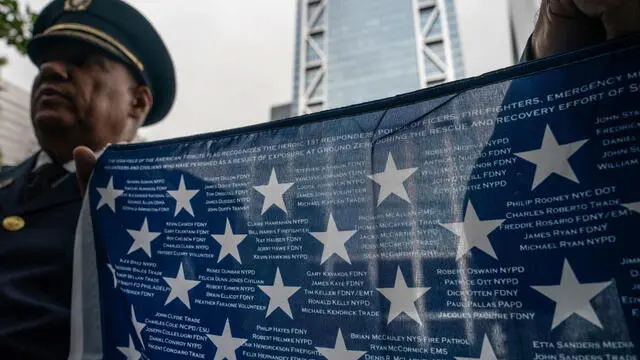 epa10854418 People hold a flag containing the names of first responders who continued to die after the 9/11 terror attacks due to exposure at Ground Zero during rescue and recovery efforts, before an annual ceremony to commemorate the 22nd anniversary of the September 11 terrorist attacks in New York, New York, USA, 11 September 2023. EPA/ADAM GRAY