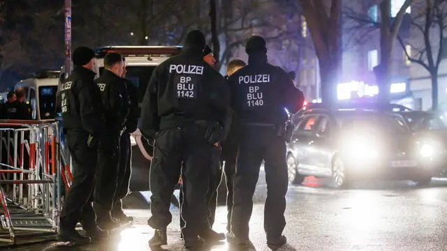 epa11051135 Police officers stand next to barriers at Sonnenallee street in the district Neukoelln in Berlin, Germany, 31 December 2023. Three pyrotechnics ban zones have been set up in Berlin. The ban applies from New Year's Eve at 6 pm until New Year's Day at 6 am. EPA/CLEMENS BILAN