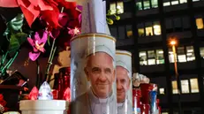 Candles with the pictures of Pope Francis are the laid under the statue of late Pope John Paul II outside Agostino Gemelli Hospital where Pope Francis is hospitalized to continues his treatments for bilateral pneumonia, in Rome, Italy, 21 February 2025. ANSA/GIUSEPPE LAMI