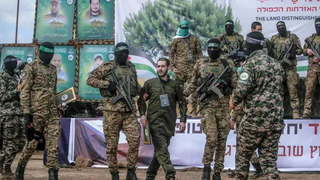 epa11915399 Fighters from Hamas' Izz ad-Din al-Qassam Brigades escort Israeli hostage Eliya Cohen before handing him over to the Red Cross in Al Nuseirat refugee camp, central Gaza Strip, 22 February 2025. Two further hostages were released earlier in the day in Rafah, southern Gaza Strip, in the final part of the first phase of the Israel-Hamas ceasefire deal. EPA/MOHAMMED SABER