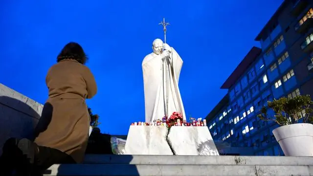 Una donna prega sotto la statua di Giovanni Paolo II all’ingresso del Policlinico Gemelli, dove è ricoverato Papa Francesco, Roma, 19 febbraio 2025. ANSA/ALESSANDRO DI MEO