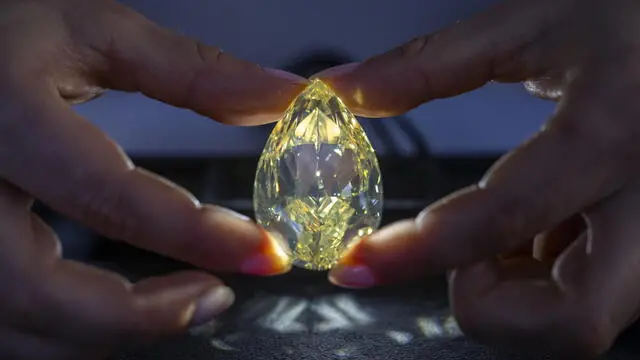 epa11329570 A Christie's employee displays the Yellow Rose, a 202-carat unmounted coloured diamond from South Africa, during a preview at the Christie's, in Geneva, Switzerland, 09 May 2024. To date there have been only two other yellow diamonds above 200ct sold at auction. It is estimated to sell for 4,000,000 Swiss Francs. The auction will take place in Geneva, on 15 May 2024. EPA/MARTIAL TREZZINI