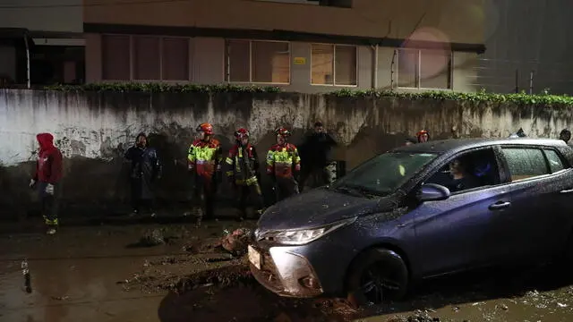 epa11256409 A driver moves his car next to first responders working in a flooded area in the La Gasca sector of Quito, Ecuador, 02 April 2024. According to police preliminary reports, at least one person died and several were trapped after floodwaters from heavy rain hit Quito's La Gasca neighborhood, where another massive flood left 29 people dead in late January 2022. EPA/Jose Jacome