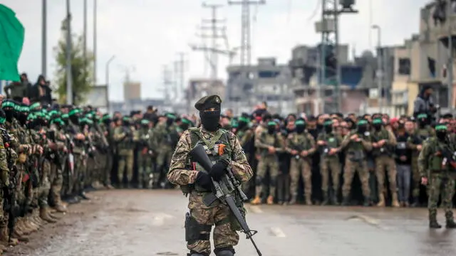 epa11915704 Armed fighters from Hamas' Izz ad-Din al-Qassam Brigades stand guard during the handover of three Israeli hostages to Red Cross representatives in Al Nuseirat refugee camp, central Gaza Strip, 22 February 2025. Six Israeli hostages were released on 22 February -- three in Nuseirat, two in Rafah and one in Gaza City -- after Hamas handed them over to the Red Cross in Gaza as part of the first phase of the Israel-Hamas ceasefire deal. EPA/MOHAMMED SABER