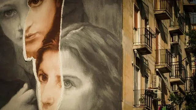 L'opera dello street artist Gomez, una riproduzione de 'La Tempesta', quadro del pittore ottocentesco William-Adolphe Bouguerau. Il murale alto oltre venti metri, è dipinto su un palazzo del Rione Luzzatti, e richiama le protagoniste della serie tv 'L'amica geniale' Lenuccia e Lina, Napoli 18 Giugno 2019. ANSA/CESARE ABBATE