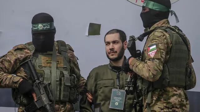 epa11915251 Fighters from Hamas' Izz ad-Din al-Qassam Brigades escort Israeli hostage Eliya Cohen before handing him over to the Red Cross in Al Nusairat refugee camp, central Gaza Strip, 22 February, 2025. Two further hostages were released earlier in the day in Rafah, southern Gaza Strip, in the final part of the first phase of the Israel-Hamas ceasefire deal. EPA/MOHAMMED SABER