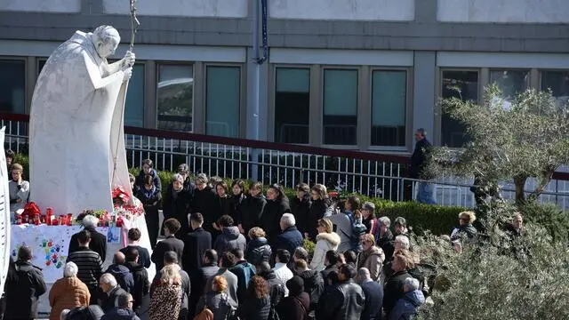 fedeli in preghiera sotto la statua di Giovanni Paolo II all'ospedale Gemelli, dov'è ricoverato Papa Francesco. Roma, 2 marzo 2025. ANSA/MASSIMO PERCOSSI