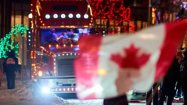 epa09751235 A supporter carries a Canadian flag near Parliament hill as truckers continue to protest in Ottawa, Ontario, Canada, 12 February 2022. Truckers continue their protest against the mandate by the Canadian government for mandatory vaccines against COVID-19 to be able to return to Canada. A state of emergency was declared in the city of Ottawa on 06 February 2022 and policemen from Ottawa city, Ontario, and the Federal Royal Canadian Mounted Police (RCMP) are deployed. EPA/ANDRE PICHETTE