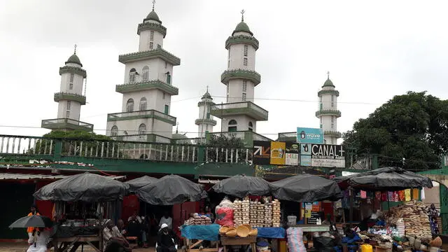 epa11932000 People sit beside stalls at a street market in front of a mosque on the first day of the holy month of Ramadan in Adjame, a suburb of Abidjan, Ivory Coast, 01 March 2025. Muslims around the world began celebrating Ramadan, the ninth month in the Islamic calendar, from the evening of 28 February 2025, which is observed by praying during the night time and abstaining from eating, drinking, and sexual acts during the period between sunrise and sunset. EPA/LEGNAN KOULA