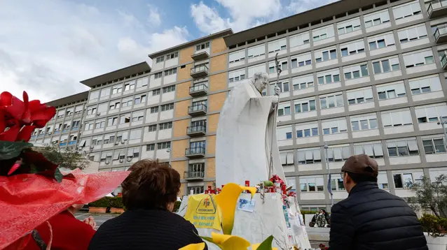 People pray under the statue of late Pope John Paul II outside Agostino Gemelli Hospital where Pope Francis is hospitalized to continues his treatments for bilateral pneumonia, in Rome, Italy, 10 March 2025. ANSA/GIUSEPPE LAMI