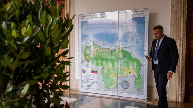 epa11023710 An official waits next to a map of Venezuela which shows the Essequibo region added to it, during a meeting of the High Commission for the Defense of Guayana Esequiba, in Caracas, Venezuela, 11 December 2023. Venezuela installed the 'High Commission for the Defense of Guayana Esequiba', which will prepare a proposal that will be presented by President, Nicolas Maduro at his meeting with his Guyanese counterpart, Irfann Ali, with whom he will address on 14 December, in Saint Vincent and the Grenadines, the territorial dispute that both countries maintain and that has escalated in recent days. The controversy grew worse after Venezuela approved a unilateral referendum annexing the Essequibo region, so the Maduro Government ordered the settlement of a military division near the disputed area, without incursions for now. EPA/RAYNER PENA R