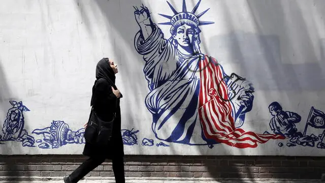 epa10686665 An Iranian woman, wearing a veil, walks next to an anti-US mural in a street in Tehran, Iran, 12 June 2023. Iran's Supreme Leader Ali Khamenei said on 11 June during a meeting with Iranian nuclear scientists, that the West could not stop Iran's nuclear progress, as he urged continued cooperation with the International Atomic Energy Agency (IAEA), amidst the scrutiny from Western powers on the country's nuclear programme. EPA/ABEDIN TAHERKENAREH