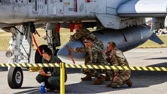 epa10681083 United States Air Force (USAF) personnel crouches in the shadow beneath a A-10 Thunderbolt plane on the airfield of the base of the 51 Tactical Air Wing Immelmann, during the NATO Air Defender 2023 exercise in Jagel, Germany, 09 June 2023. The 'Air Defender 2023' maneuver is the largest North Atlantic Treaty Organization (NATO) redeployment exercise of air forces in its existence and takes place from 12 to 23 June gathering up to 10,000 participants from 25 nations with 250 aircraft to train air operations in European airspace under the command of the German Air Force, the German Armed Forces (Bundeswehr) explains on their website. EPA/HANNIBAL HANSCHKE