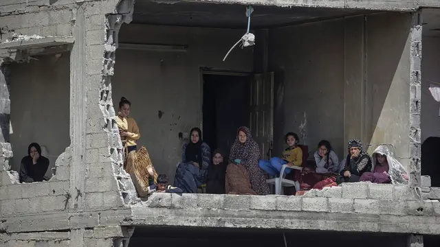 epa11973832 A Palestinian family sits inside a damaged house as they watch people searching for bodies and survivors among the rubble of another house (not pictured) belonging to the Hattab family following an Israeli airstrike in Gaza city on 19 March 2025. According to the Palestinian Ministry of Health in Gaza, an Israeli airstrike killed at least four members of the Hattab family. On 18 March Israeli forces resumed airstrikes on Gaza ending a ceasefire held in place since 19 January and killing over 400 people, the Health Ministry confirmed. EPA/MOHAMMED SABER