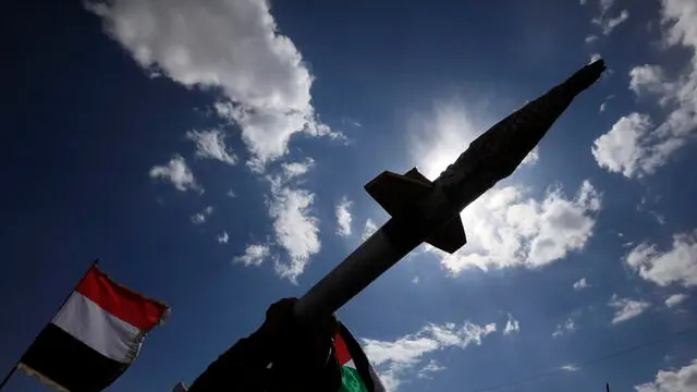 epa11970462 A Houthi supporter carries a mock missile as others wave the flags of Palestine (R) and Yemen (L) during a protest in Sana'a, Yemen, 17 March 2025 against US airstrikes on Houthi positions. Houthi supporters have taken to the streets of Sana'a to protest the airstrikes that targeted Houthi-held positions in several Yemeni cities on 15 March. The Houthis have vowed to target US ships in the Red Sea in retaliation for the recent US airstrikes that killed at least 53 people and wounded 98 others, according to a statement by Houthi military spokesman Yahya Sarea. EPA/YAHYA ARHAB