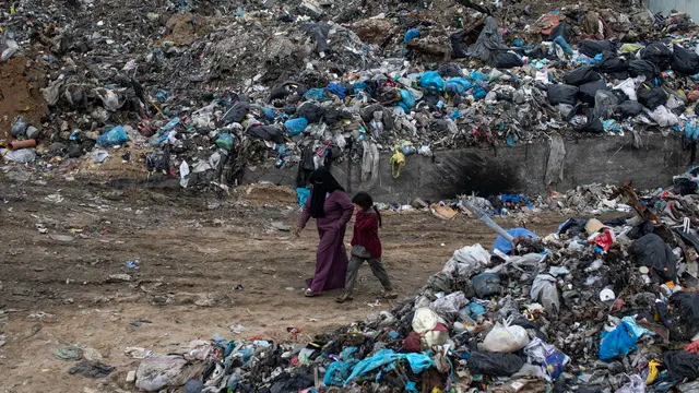 epa11979236 Displaced Palestinians walk in a garbage dump in the Yarmouk area of â€‹â€‹Gaza City, the Gaza Strip, 21 March 2025, after the Israeli army issued evacuation orders for the northern areas of the city. EPA/HAITHAM IMAD