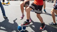 Alcuni ragazzi giocano a calcio in strada a Milano, 13 aprile 2024, ANSA/DAVIDE CANELLA