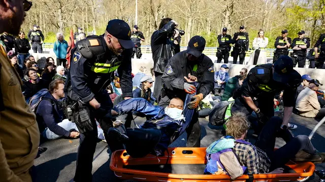 epa12011395 Police officers remove Extinction Rebellion protesters at the entrance to the A12 Utrechtsebaan tunnel trench in The Hague, the Netherlands, 05 April 2025. The climate action group wants to block the A12 to demonstrate against the provision of fossil subsidies. EPA/SEM VAN DER WAL