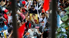 epa10442278 Protesters flash the three finger salute while holding pictures of Myanmar democracy icon Aung San Suu Kyi during a demonstration to mark the second anniversary of Myanmar's 2021 military coup, outside the Embassy of Myanmar, in Bangkok, Thailand, 01 February 2023. Myanmar migrant workers rallied outside the Myanmar embassy marking the second anniversary of the 2021 Myanmar military coup. EPA/DIEGO AZUBEL