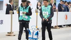 epa12040203 A robot and its engineers run in a marathon in Beijing, China, 19 April 2025. China hosts the worldâ€™s first all-robot marathon in Beijing, showcasing the speed, agility, and performance of humanoid robots. EPA/JESSICA LEE