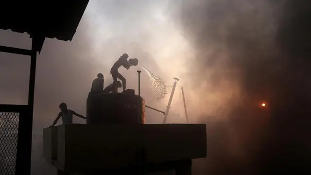 epa11838518 Locals work to extinguishing the flames after a fire broke out at a rubber goods factory in Park Circus suburban railway station in Kolkata, Eastern India, 20 January 2025. No casualties have been reported by police in a major fire that broke out. EPA/PIYAL ADHIKARY