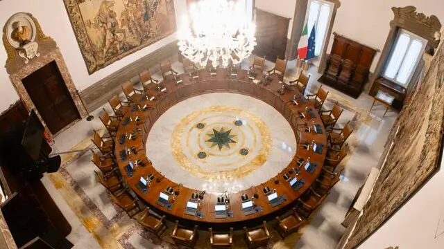 Il tavolo rotondo della sala in cui si tiene il Consiglio dei ministri, Roma, 30 gennaio 2025. A partire dal marzo 1961, anno in cui Palazzo Chigi diventa sede della Presidenza del Consiglio, la Sala del Consiglio dei ministri ospita le riunioni dell’esecutivo. La sala ha il soffitto decorato con travi di legno, al di sotto del quale si dispiega un fregio decorato nel 1665 dal pittore austriaco Giovanni Paolo Schor. Il fregio è realizzato con una finta architettura ad archi che inquadra una serie di figure mitologiche a mezzobusto sullo sfondo di paesaggi boscosi. Spiccano sulle pareti due grandi arazzi, realizzati dal fiammingo Jan Leyniers e acquistati dai Chigi nel 1668, raffiguranti le storie della vita di Alessandro Magno. Nella Sala è collocato un caminetto di fine 1700 di marmo bianco finemente intagliato e con tre medaglioni di alabastro e figure di bronzo dorato; completano l'arredamento gli scranni in legno di un antico coro di gusto cinquecentesco. (simbolica, generica, vuoto, cdm) ANSA / FILIPPO ATTILI - UFFICIO STAMPA PALAZZO CHIGI +++ NO SALES - EDITORIAL USE ONLY+++