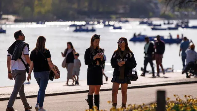 epa12025777 People walk along the Serpentine recreational lake in Hyde Park as they enjoy the warm weather and sunshine with the temperatures climbing up to 23 degrees Celsius in London, Britain, 11 April 2025. EPA/TOLGA AKMEN