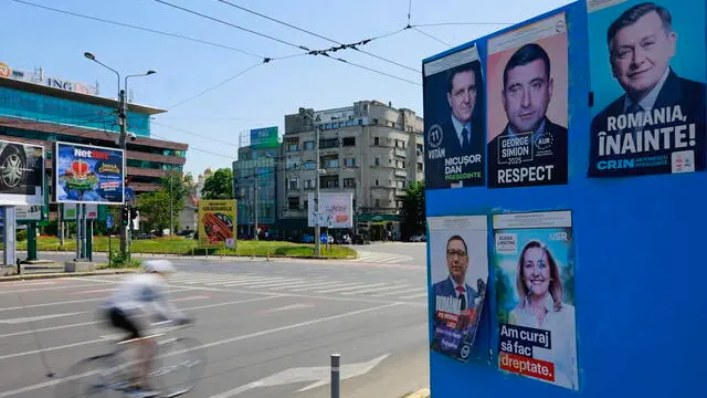 epa12069543 A cyclist speeds past a billboard displaying electoral posters of candidates for the 2025 presidential elections, in Bucharest, Romania, 02 May 2025. Romanians will vote in the first round of the presidential elections on 04 May 2025. EPA/ROBERT GHEMENT