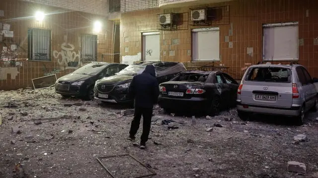 epa11816379 A local person stands near damaged cars at the site of drone debris falling on a residential building, in Kyiv, Ukraine, 10 January 2025, amid the Russian invasion. Debris of a Russian unmanned aerial vehicle (UAV) hit a high-rise building in the Solomianskyi district of Kyiv, the head of the Kyiv City Military Administration, Tymur Tkachenko wrote on telegram, adding that no injuries were reported in the incident. EPA/SERGEY DOLZHENKO