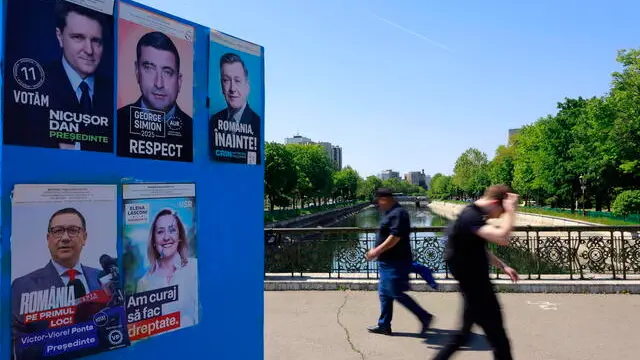epa12069542 Two men pass by a billboard displaying electoral posters of candidates for the 2025 presidential elections, in Bucharest, Romania, 02 May 2025. Romanians will vote in the first round of the presidential elections on 04 May 2025. EPA/ROBERT GHEMENT
