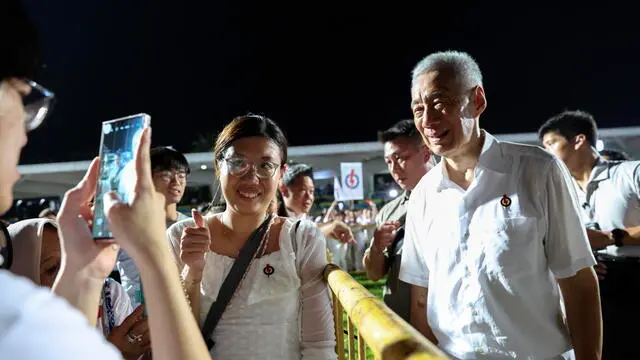 epa12071661 Singapore's Senior Minister Lee Hsien Loong (R) poses for a photo with a supporter after the preliminary results of the general elections were announced in Singapore, 04 May 2025. Singaporeans go to the polls to elect 97 members of Parliament across 33 constituencies, five of which have already been secured by the ruling People's Action Party (PAP) through a walkover. EPA/HOW HWEE YOUNG