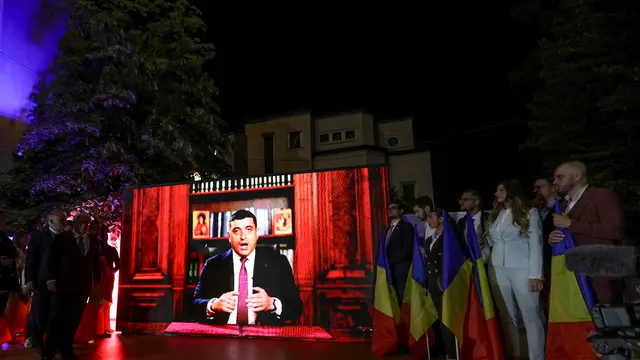 epa12073734 Alliance for the Union of Romanians (AUR) party leader George Simion is displayed delivering a speech on a screen at the AUR party headquarters in Bucharest, Romania, 04 May 2025. According to exit polls, ultra-nationalist party AUR leader George Simion is projected to qualify for the presidential runoff on 18 May. EPA/ROBERT GHEMENT